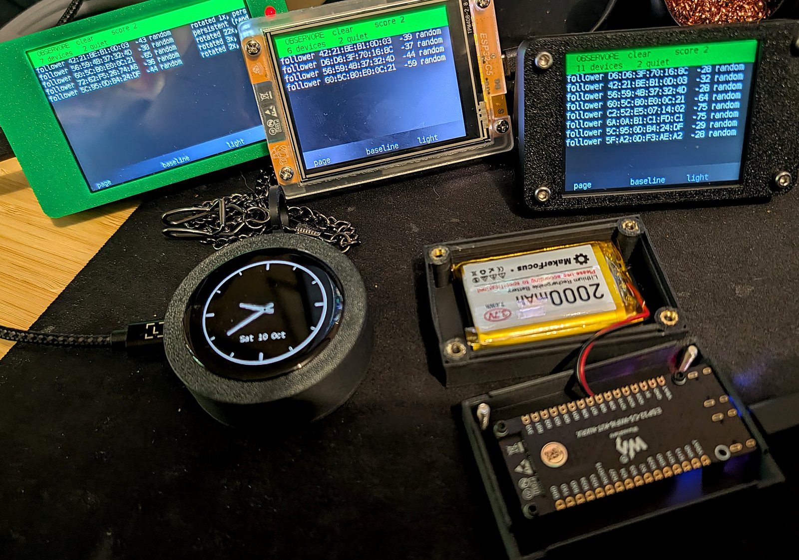 Three Cheap Yellow Display boards showing Observore's clear verdict and follower lists, a round AMOLED board in a pocket-watch case showing a clock face, and an open case holding a bare board wired to a 2000 mAh lithium cell